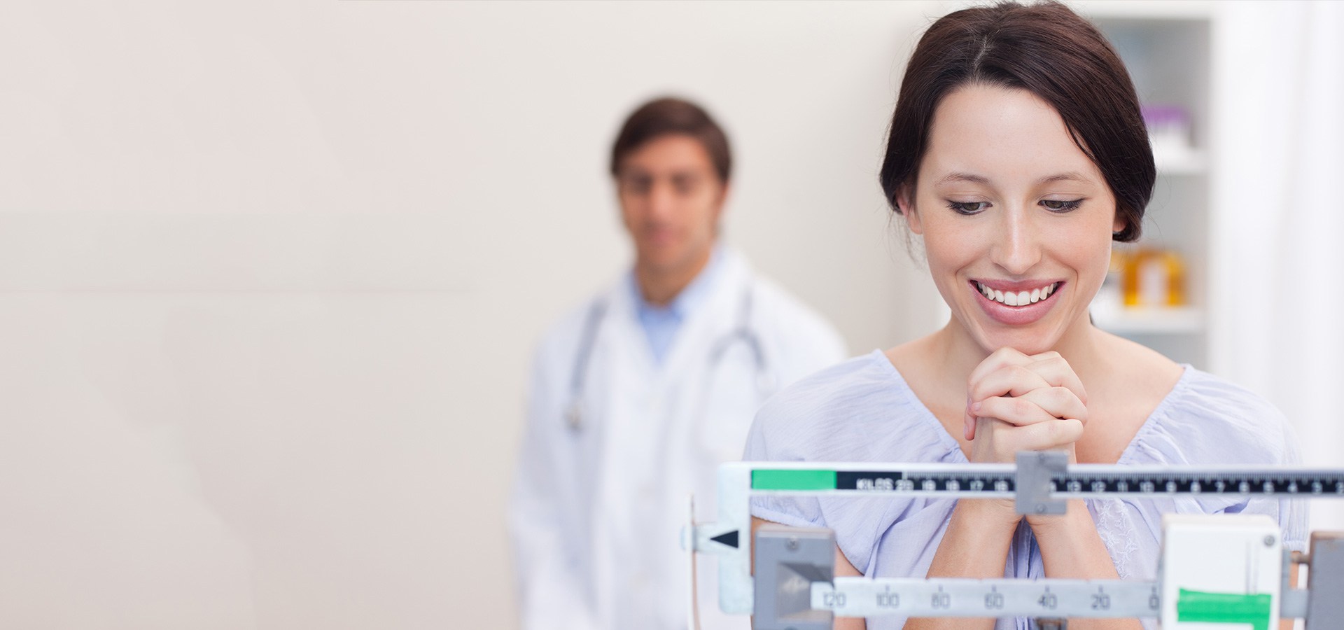 Patient smiling on medical scale with doctor